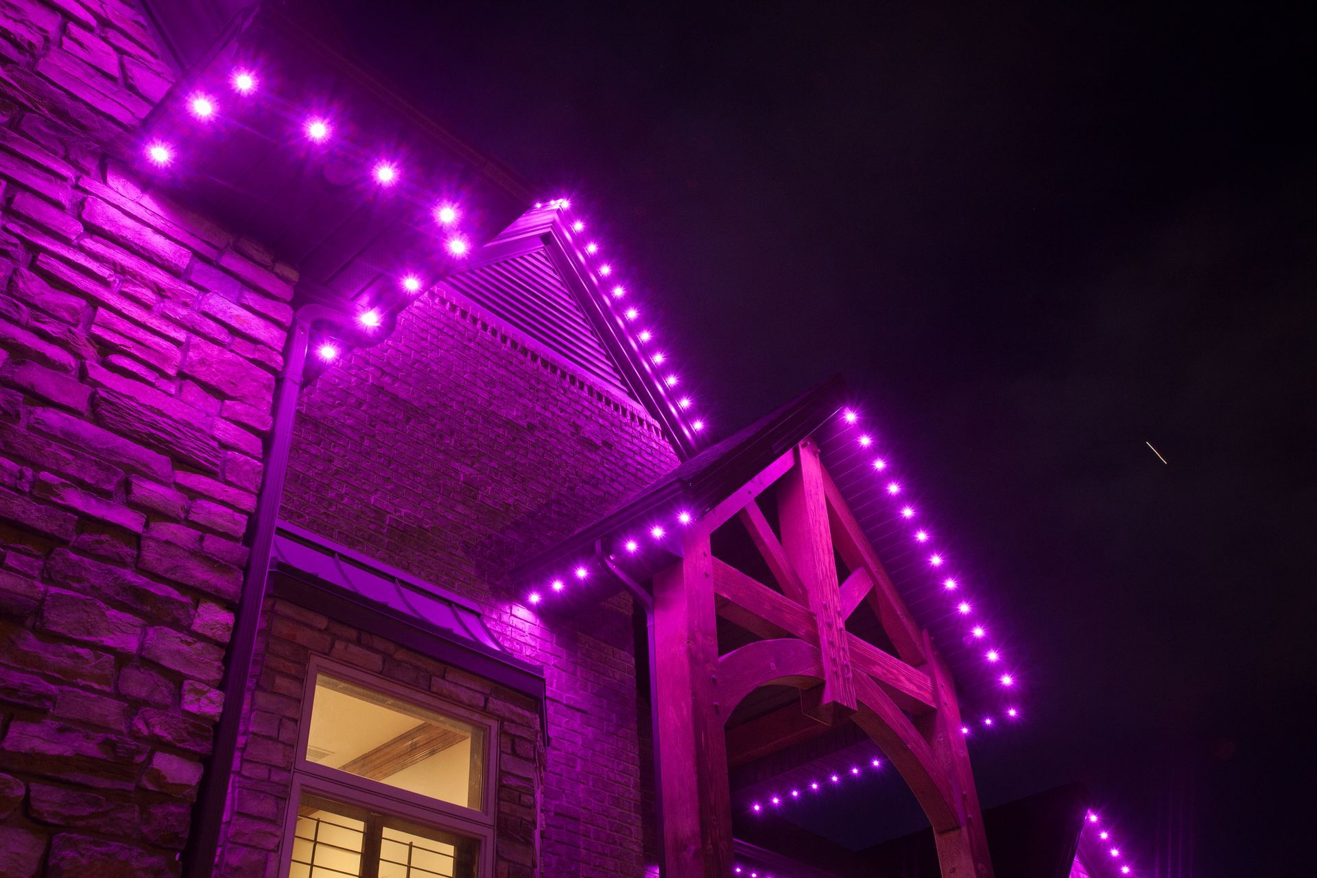 A house with purple lights on the side of it at night.
