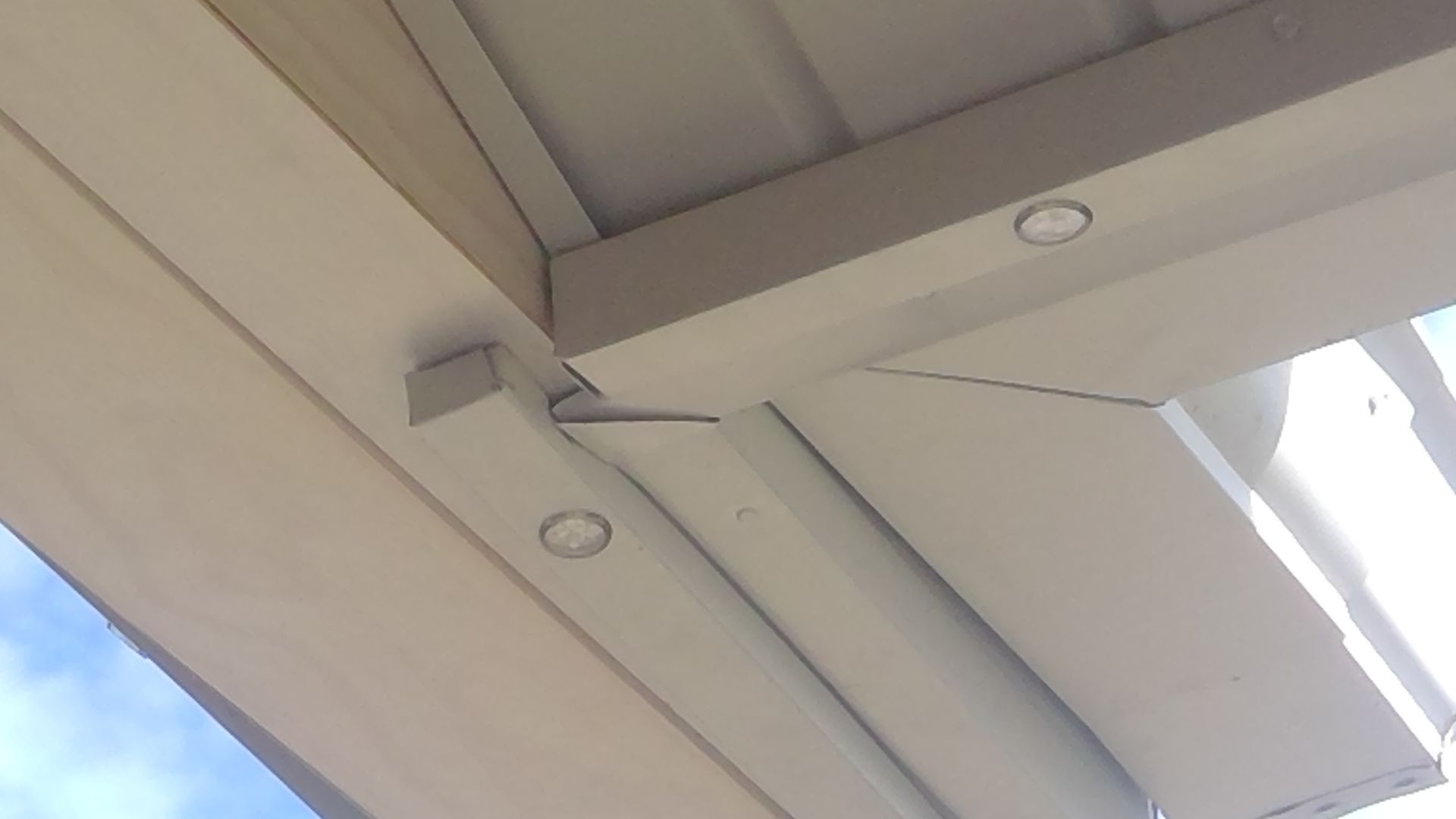 A close up of the ceiling of a building with a blue sky in the background.