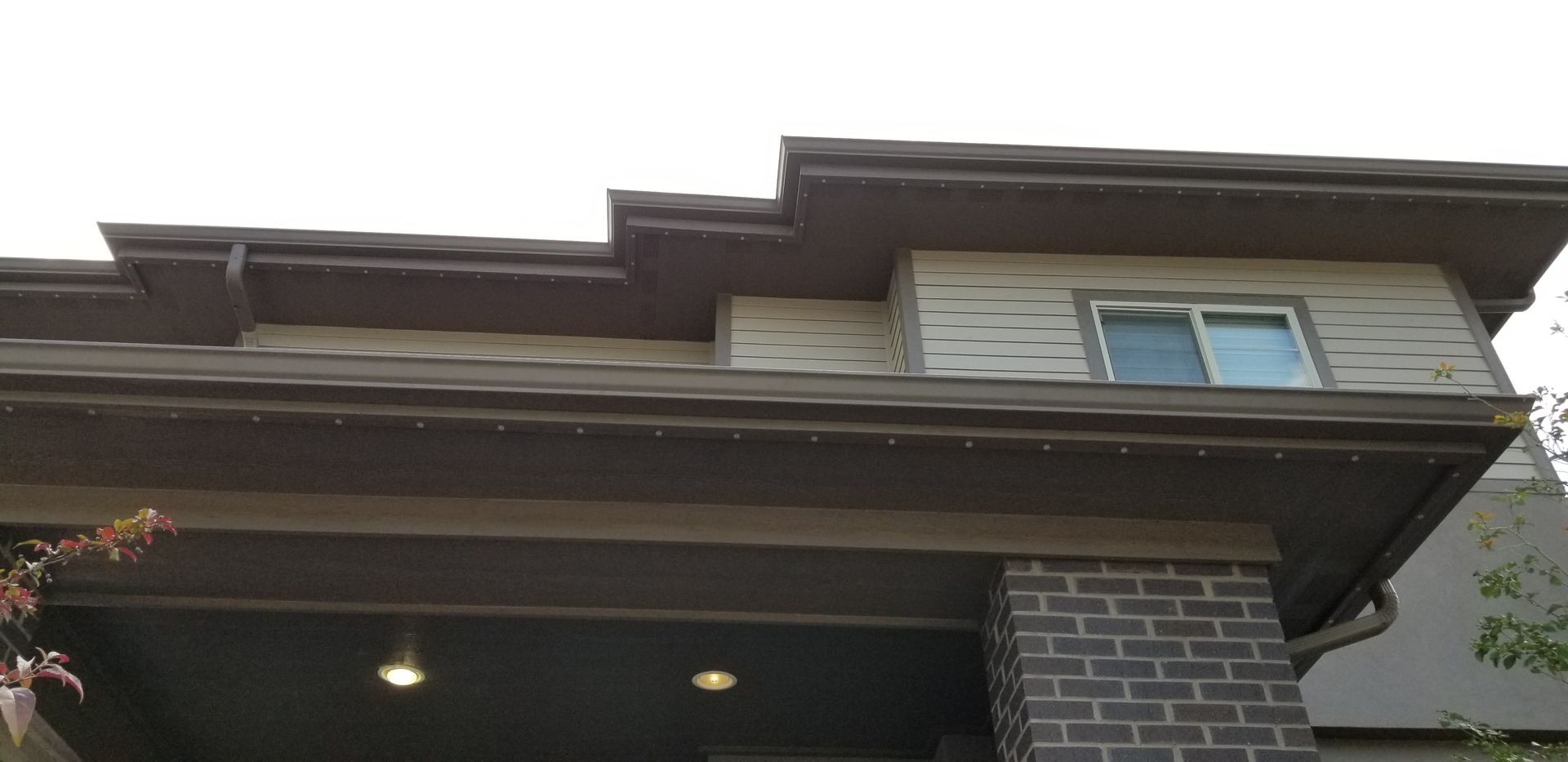 The roof of a house with a brick chimney and a window.