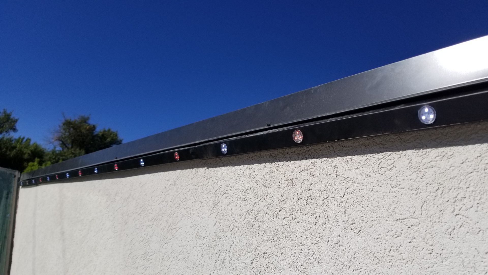A white wall with a metal roof and a blue sky in the background.