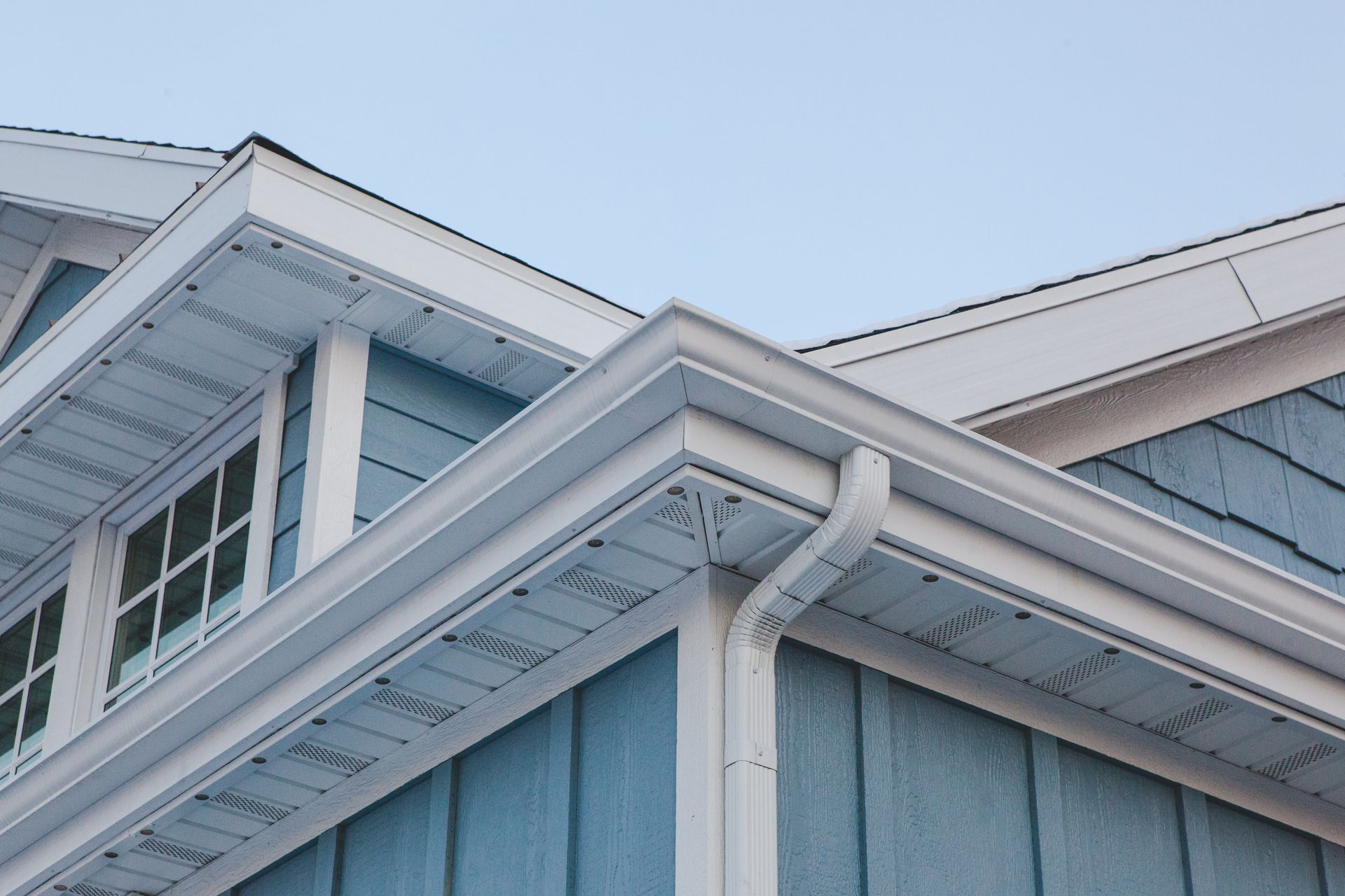 A blue house with a white gutter on the side