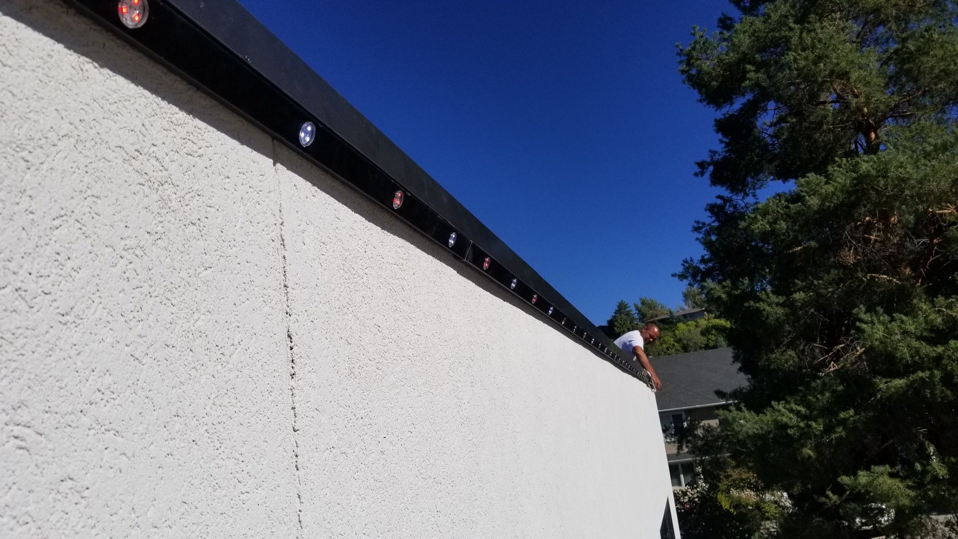 A man is standing on top of a white wall.