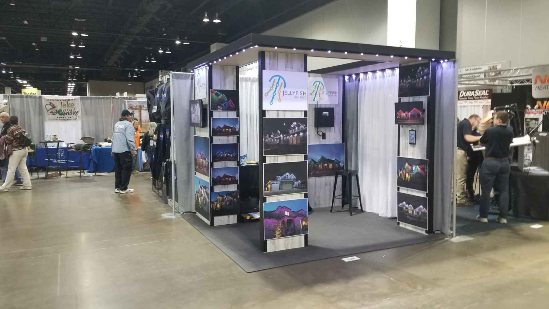 A group of people are standing around a booth at a convention.