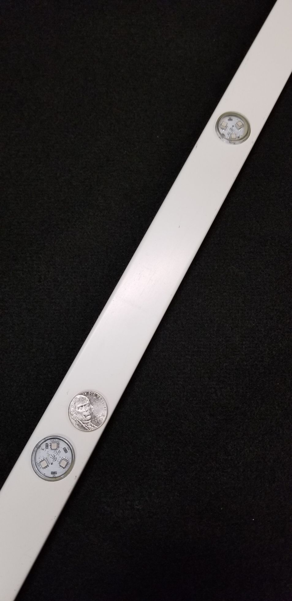 A white strip with buttons on it is sitting on a black surface.