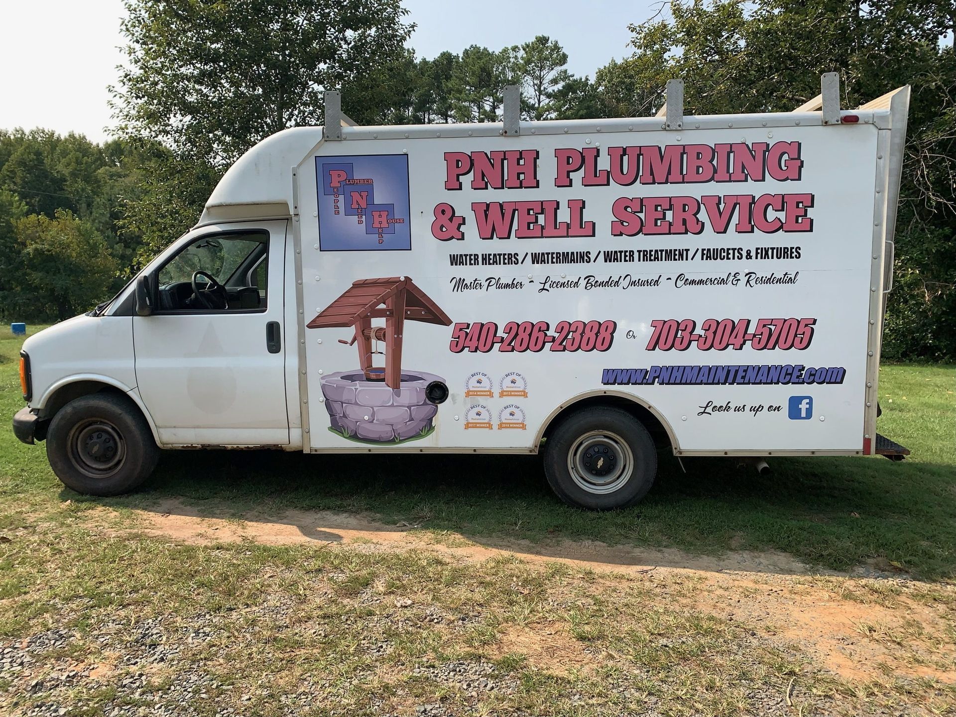 A plumbing and well service van is parked in a grassy field.