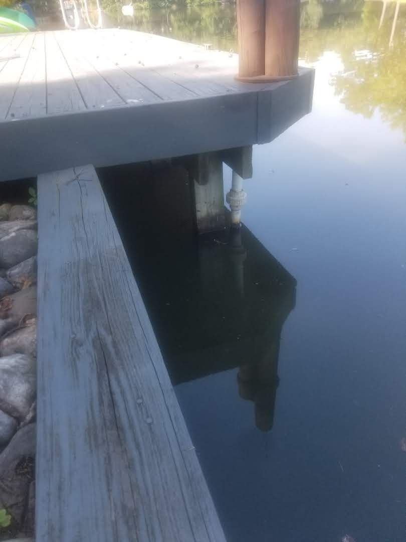 A wooden dock is sitting next to a body of water.