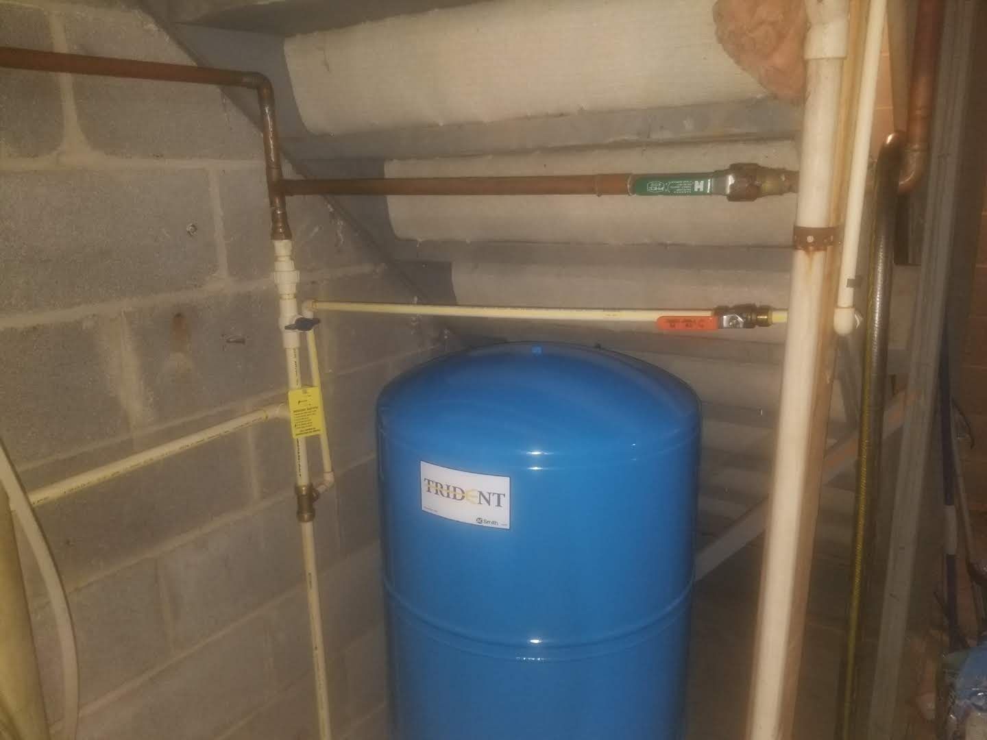A blue water tank is sitting in a room next to a brick wall.