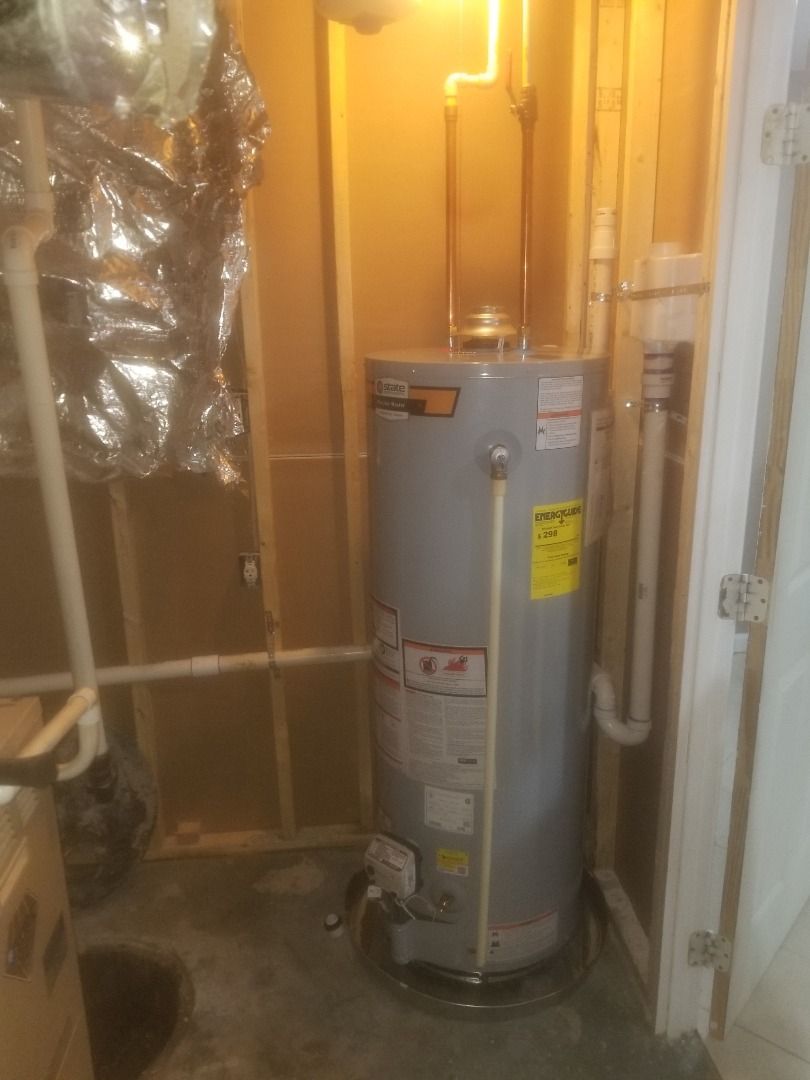 A water heater is sitting in a room next to a door.
