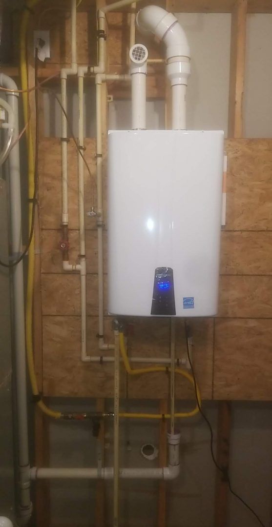 A white water heater is sitting in a basement next to pipes.