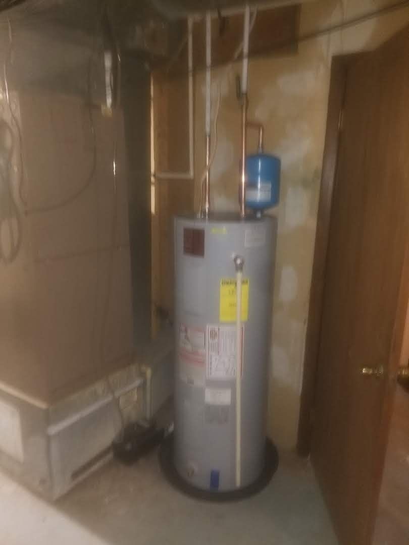 A water heater is sitting in a room next to a door.