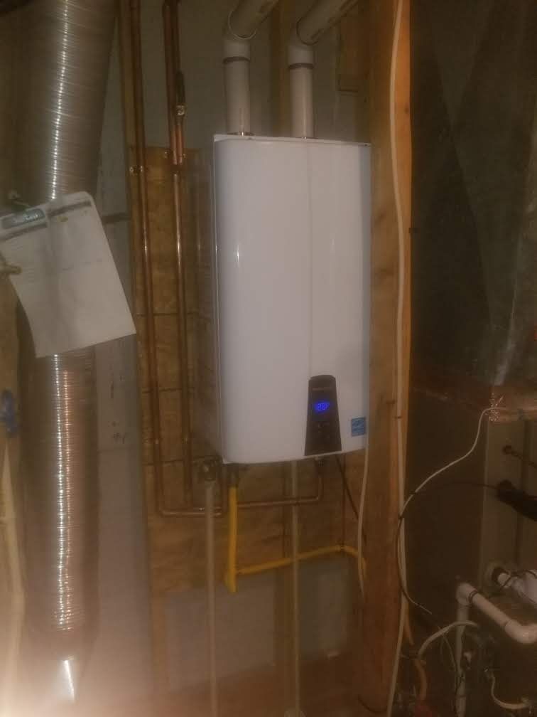 A white water heater is sitting in a basement next to pipes.