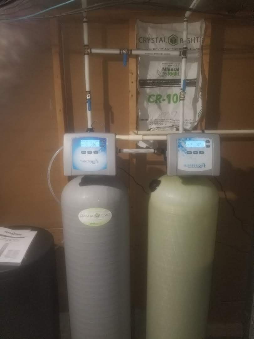 Two water filters are sitting next to each other in a basement.