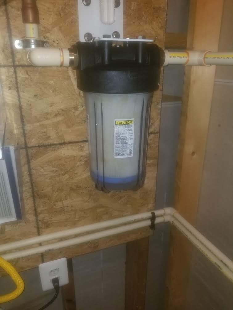 A water filter is hanging on a wall in a basement.