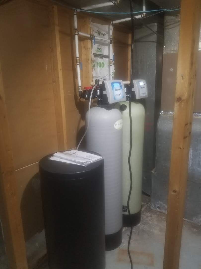 A water filter is sitting in a basement next to a heater.