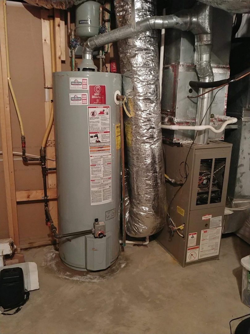A gas water heater is sitting in a basement next to an air conditioner.