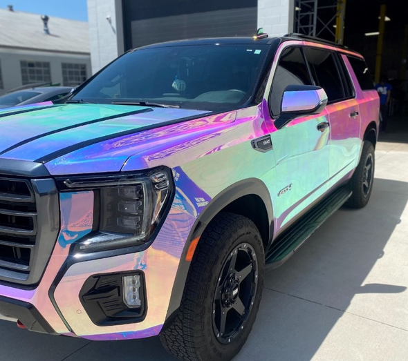 A rainbow colored suv is parked in front of a building