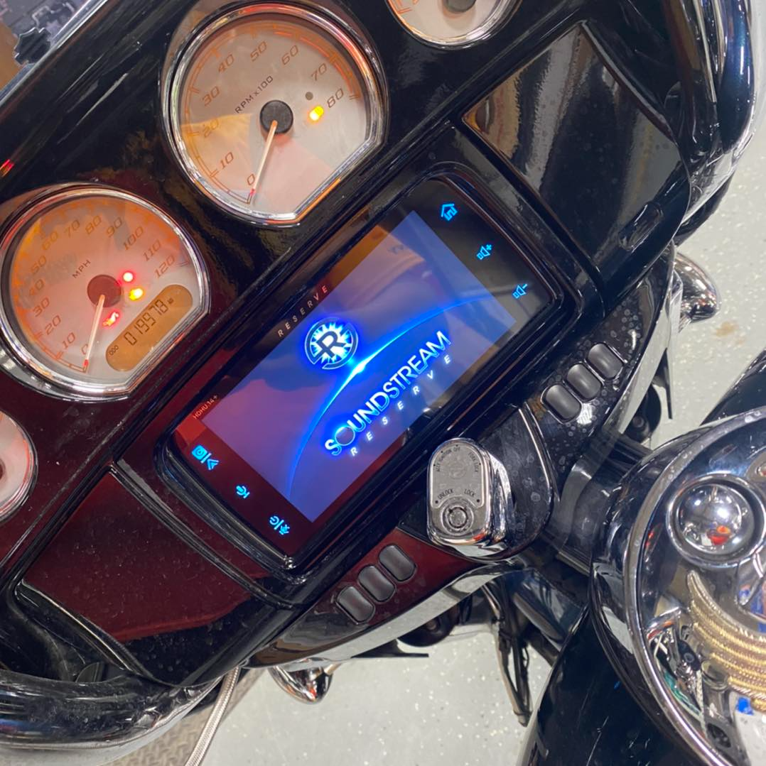 A motorcycle dashboard with a screen that says soundstream