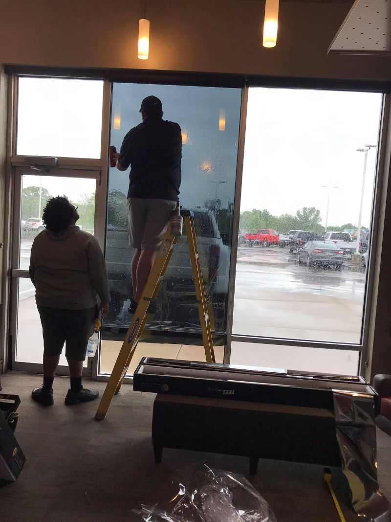 A man is standing on a ladder cleaning a window.