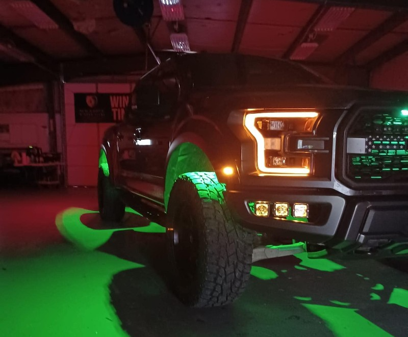 A truck is lit up with green lights in a garage