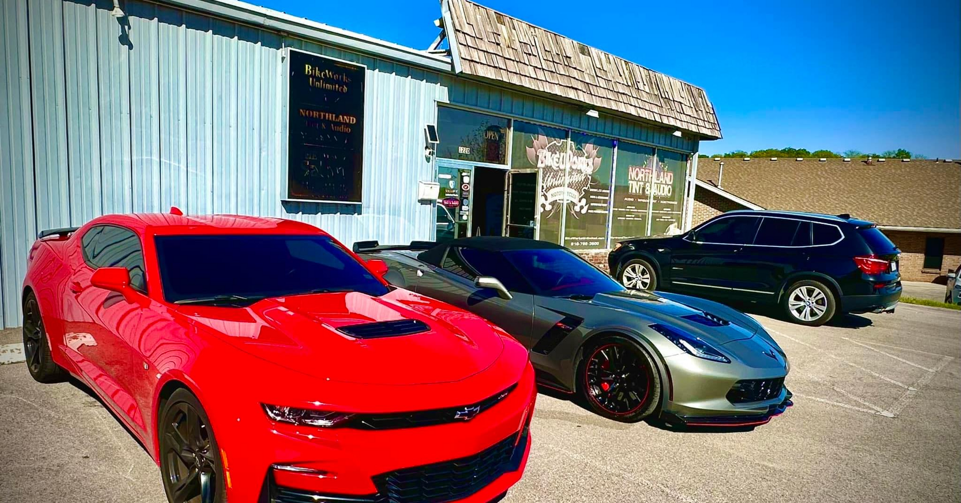 Three sports cars are parked in front of a building.