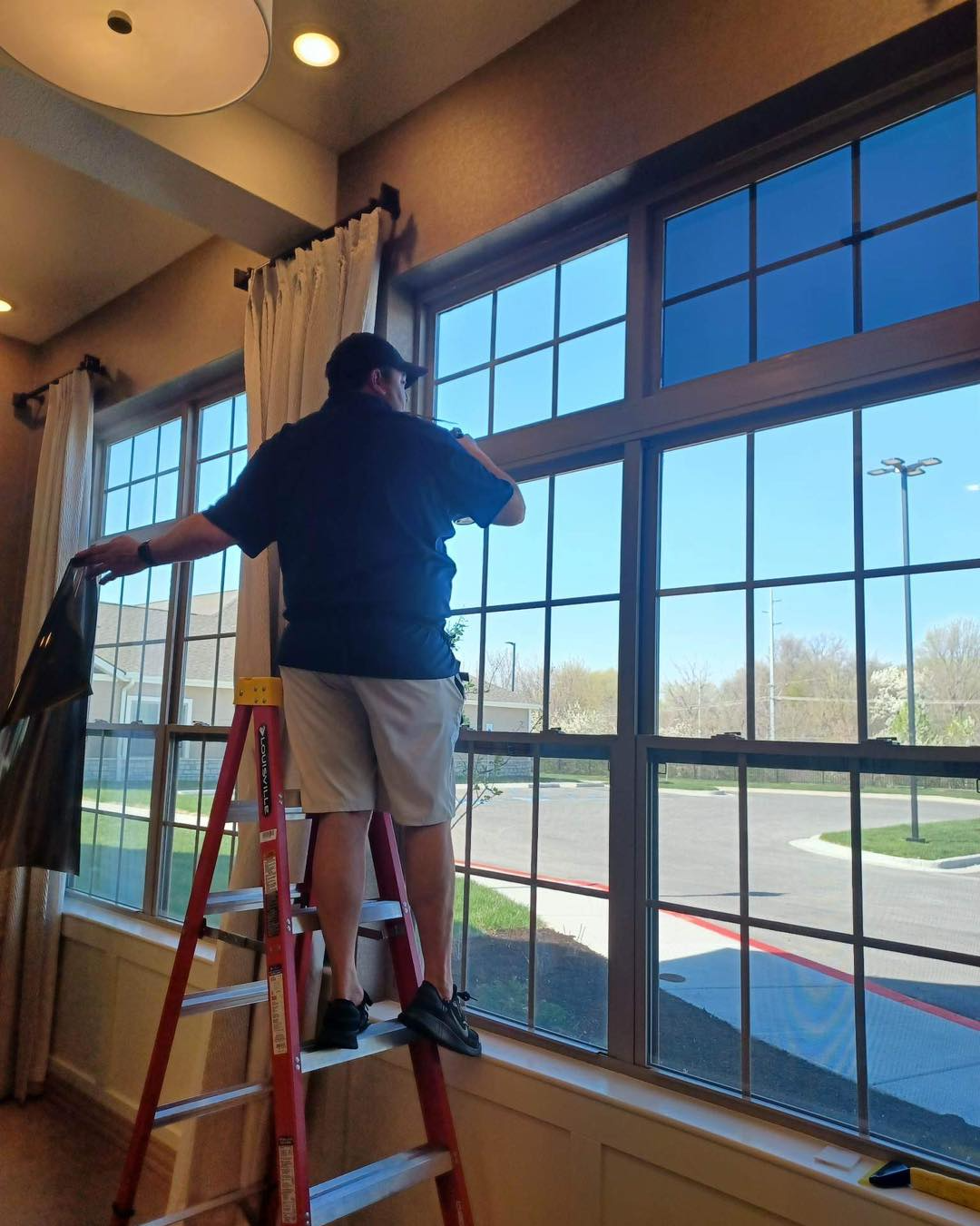 A man is standing on a ladder cleaning a window.