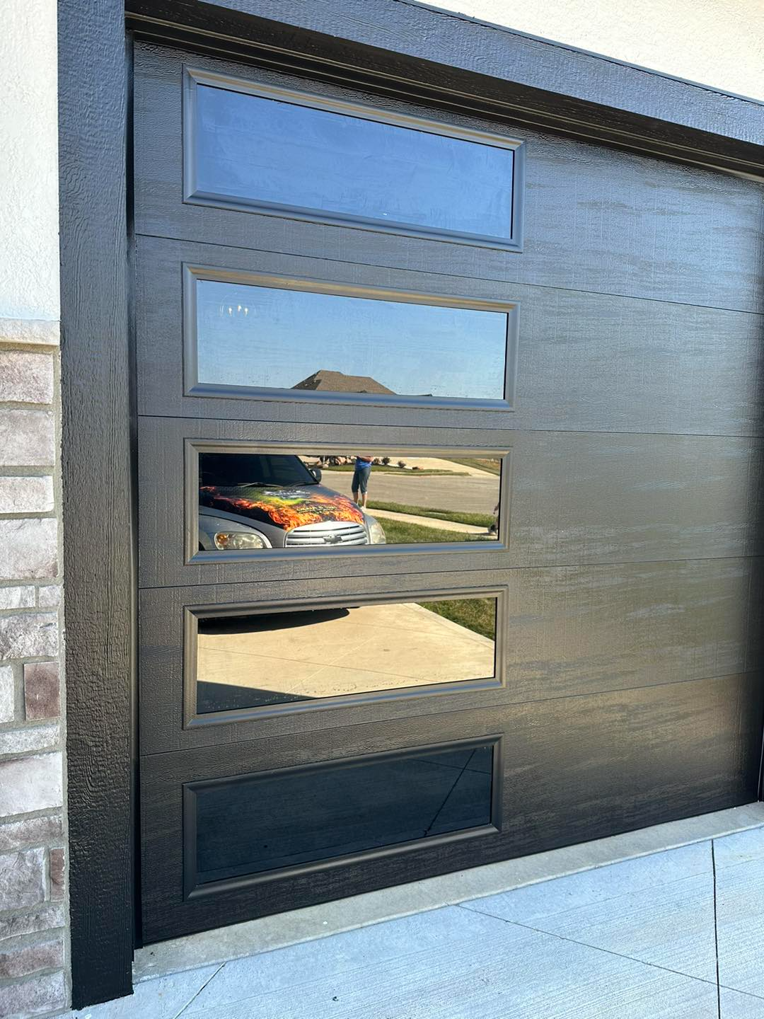 A black garage door with a reflection of a car in it.