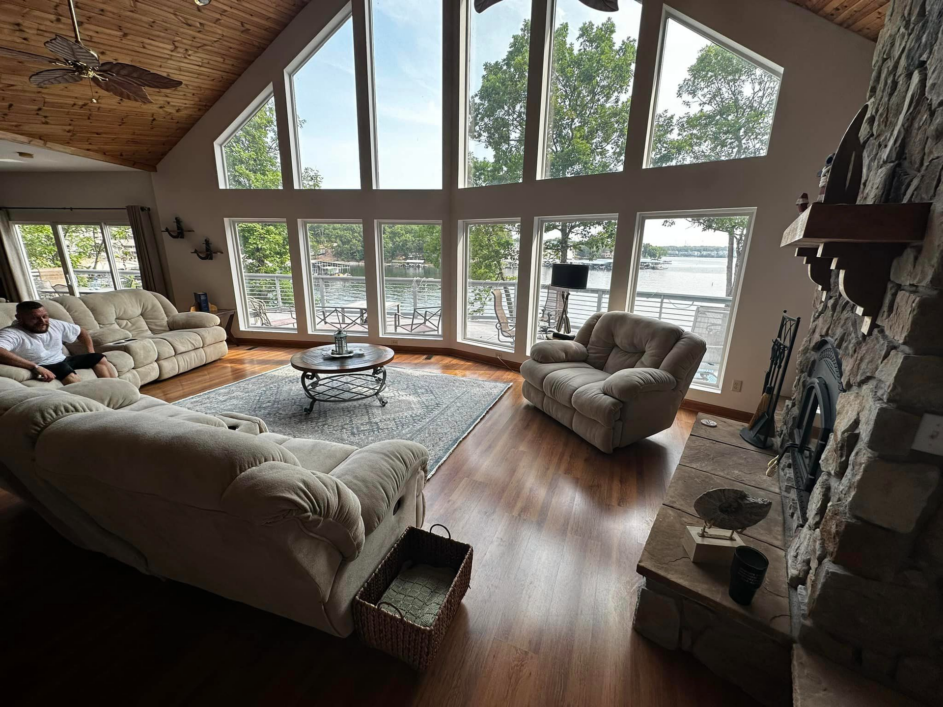 A man is sitting on a couch in a living room with a lot of windows.