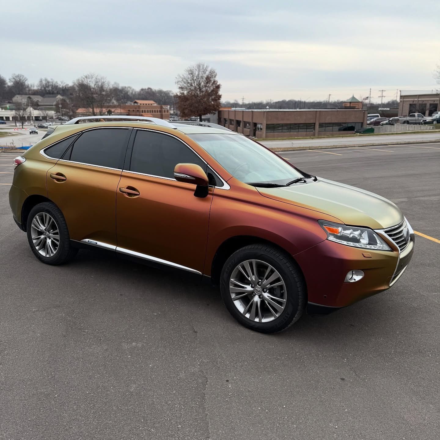 A Lexus SUV parked in a lot, featuring a custom color-shifting paint job that transitions between metallic gold and red.