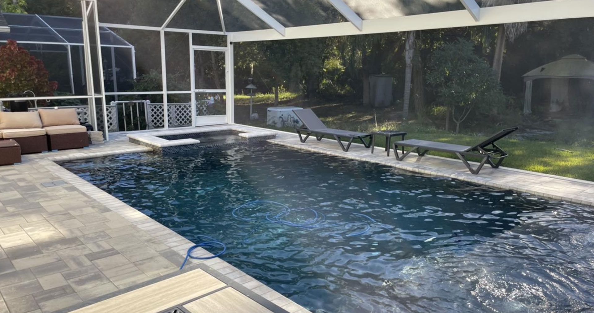 Swimming pool with lounge chairs, screened enclosure, and landscaping.