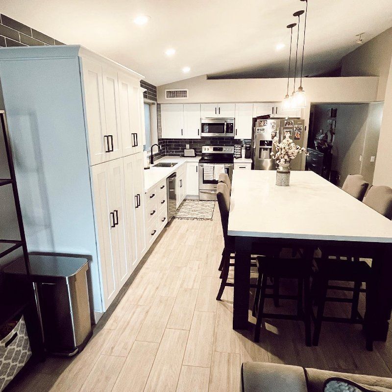 A kitchen with white cabinets and a long table