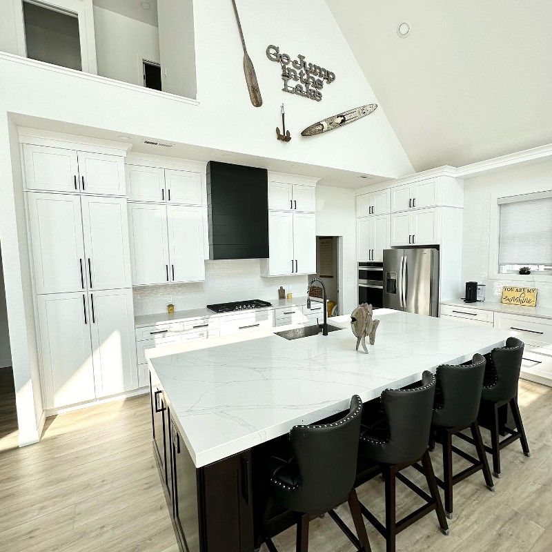 A kitchen with white cabinets and a large island in the middle.