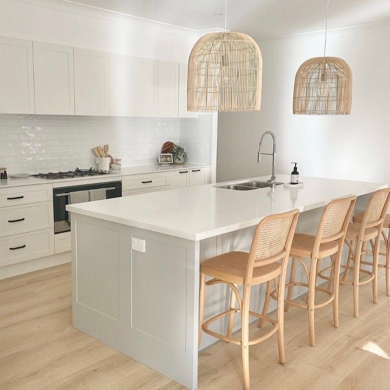A kitchen with a large island and wicker chairs.