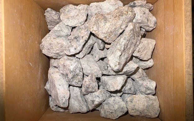 Pile of gray rocks inside a wooden container.