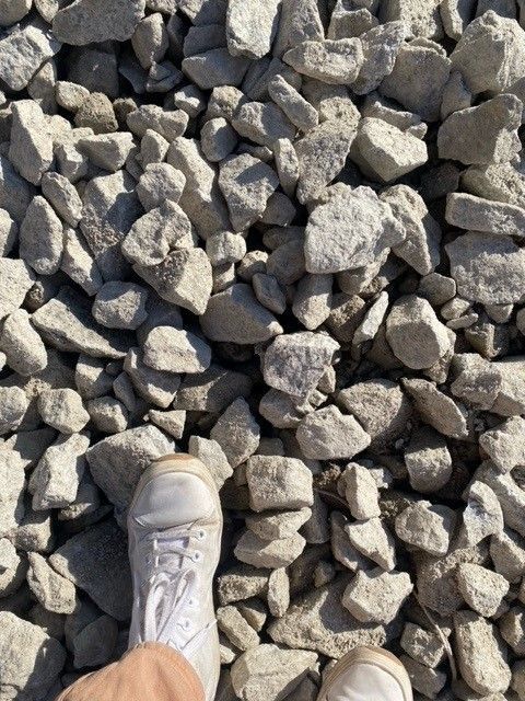 Foot in white shoe among gray gravel.