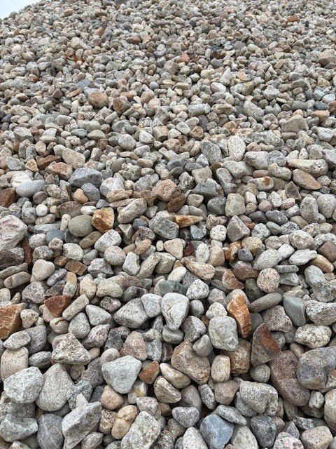 Pile of mixed-color river rock; ranging from gray to brown, varying in size.