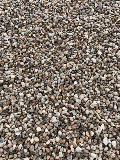 Close-up of a pile of small, smooth, rounded pebbles in various shades of brown, gray, and tan.