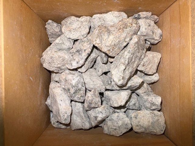 Gray rocks fill a wooden box.