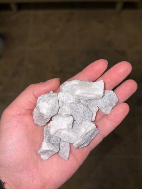 Hand holding a pile of small, light gray rocks.