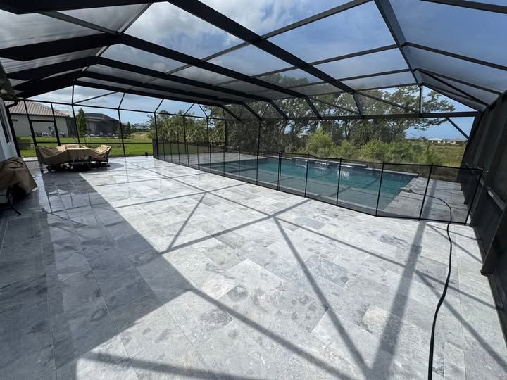 Pool patio with enclosed screen, gray tile, and pool.