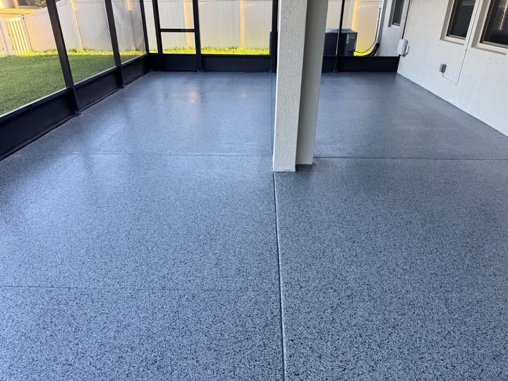 Blue speckled epoxy-coated patio floor. Screened enclosure with white support column and exterior wall.