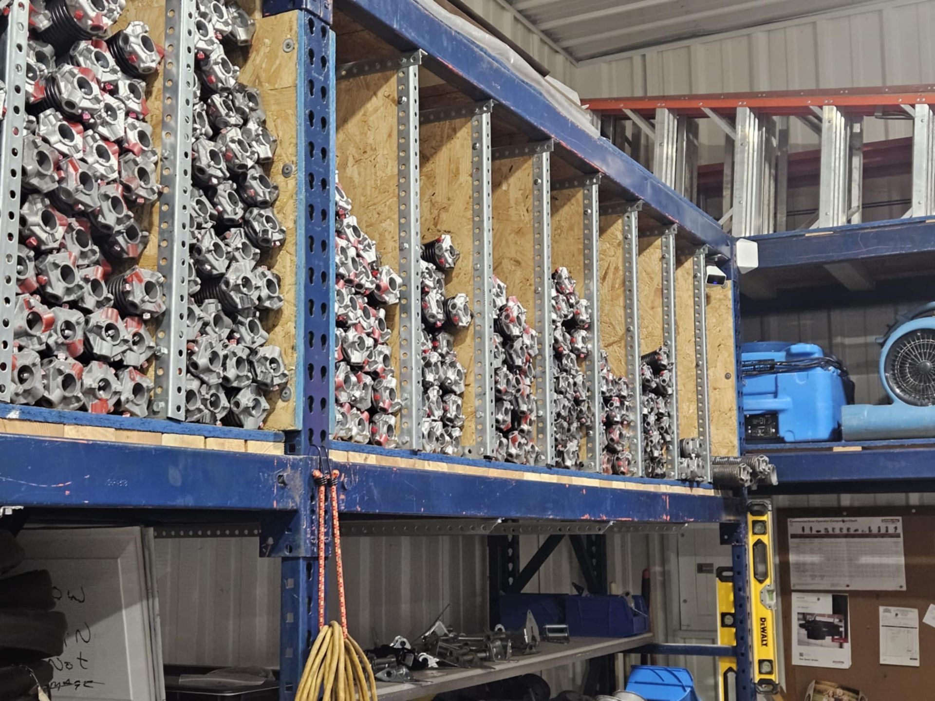 Industrial shelving unit filled with organized stacks of metal engine parts in a warehouse setting.