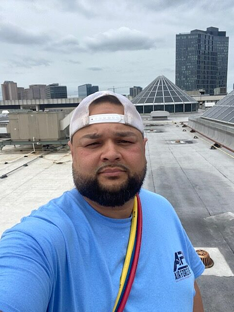 a man in a blue shirt is taking a selfie on a rooftop