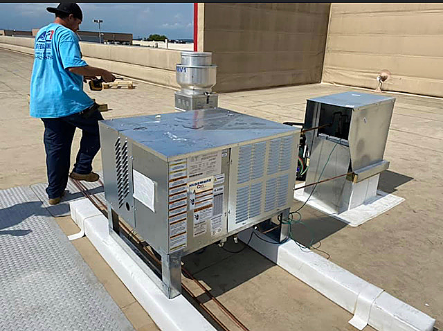 a man in a blue shirt is working on a machine on a roof .