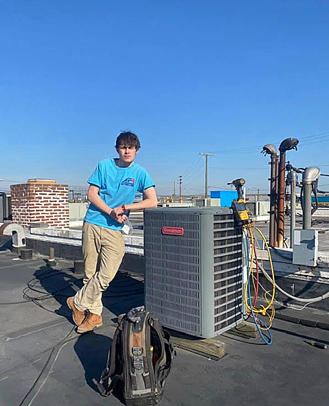 a young man is standing on top of a roof next to an air conditioner .