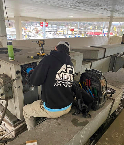 a man in a black hoodie is working on a machine .