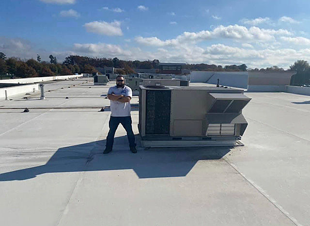 a man is standing on the roof of a building with his arms crossed .