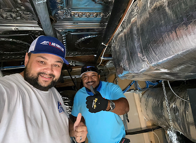 two men are standing next to each other in a room giving a thumbs up .