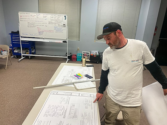 a man is standing in front of a table with a drawing on it .