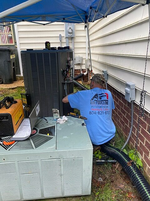 a man in a blue shirt is working on an air conditioner outside of a house .