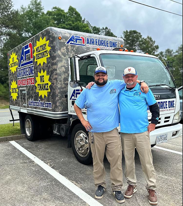two men are posing for a picture in front of an air force one truck .